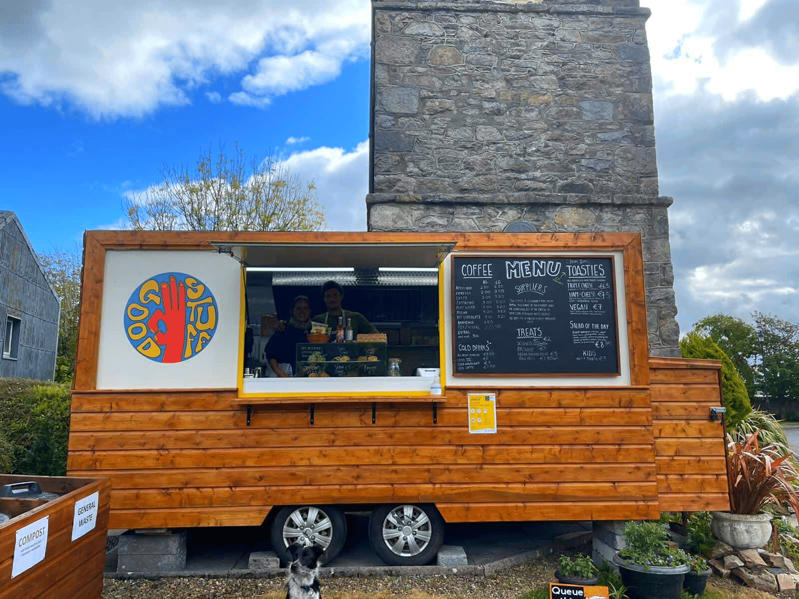 a wooden coffee and food truck with two people inside the van 